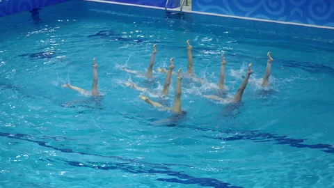 Synchronized swimmers gracefully perform mesmerizing routines on a colorful Vídeos de archivo 311366746
