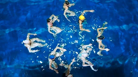 Synchronized swimming. Young girls learn swimming in the pool. Young girls are Stock Footage