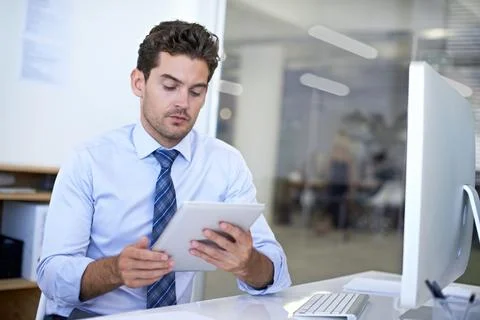 Synchronizing his data between devices. A young businessman using a digital Stock Photos