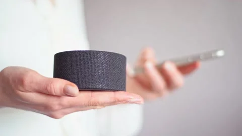 Synchronizing phone and a portable voice assistant speaker to control a smart Stock Footage 130751678
