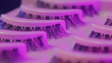 Synthetic false lashes illuminated by vibrant neon lighting. Modern studio setup Video stock 334551094