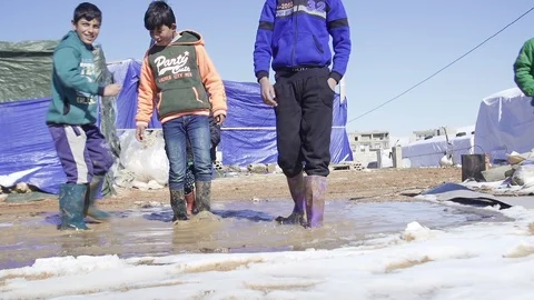 Syrian refugee boys trample mud and snow with their boots in Beqaa, Lebanon Video stock 119436311