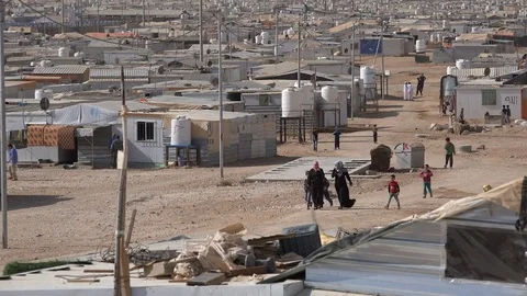 Syrian refugees walk past makeshift homes in the Zaatari camp in Jordan Stock Footage