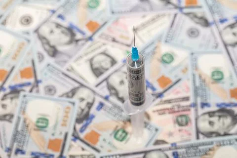Syringe with 100 dollar banknote inside on dollar banknotes Stock Photos