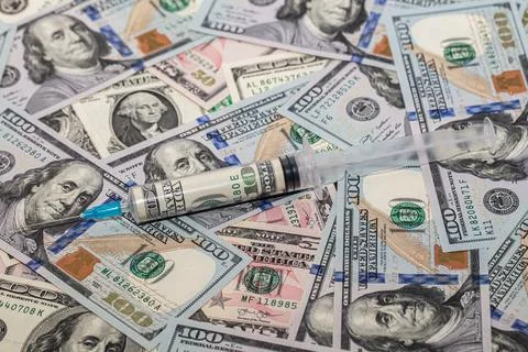 Syringe with 100 dollar banknote inside on dollar banknotes Stock Photos