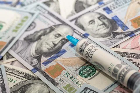 Syringe with 100 dollar banknote inside on dollar banknotes Stock Photos