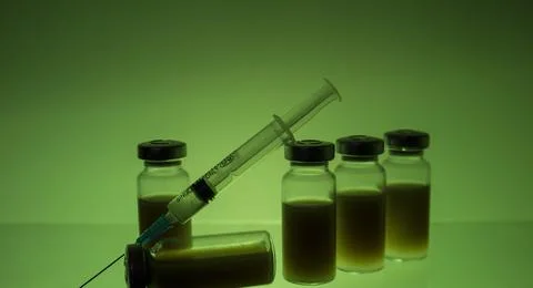 A syringe and five test tubes filled with medicine. Stock Photos