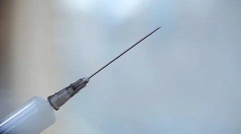Syringe and needle with drop of liquid on light Stock Footage 61628070