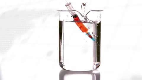 Syringe approaching beaker, needle piercing liquid, making splash and bubbles to Stock Footage 323274484