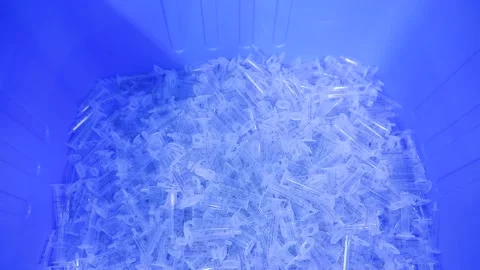 Syringe barrels fall onto a plastic container Stock Footage 163088096