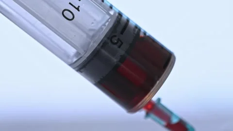 A syringe is being used to inject a red liquid into a person Stock Footage 313554498