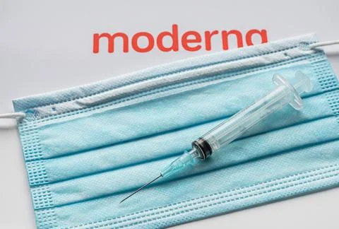 Syringe on a blue facemask withe the moderna logo Stock Photos