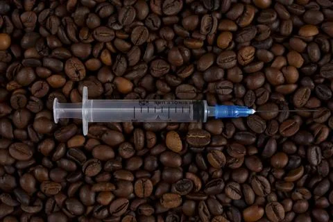 Syringe on coffee beans background Stock Photos