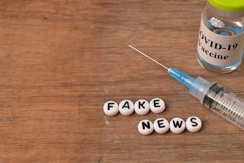 Syringe, Covid-19 bottle vaccination and alphabet beads with text FAKE NEWS Stock Photos