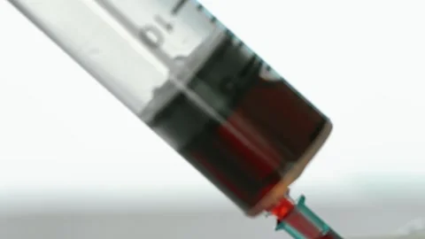 A syringe filled with red liquid is being used to inject a patient Stock Footage 313416970