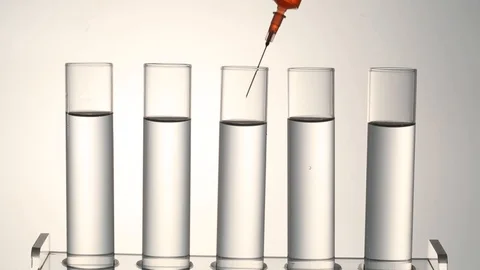 Syringe injecting red liquid in test tubes Stock Footage 95967619