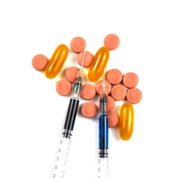 A syringe with an injection solution and vitamins with pills Stock Photos