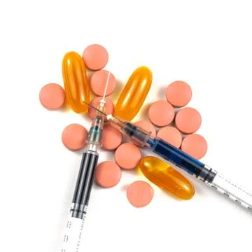 A syringe with an injection solution and vitamins with pills Stock Photos