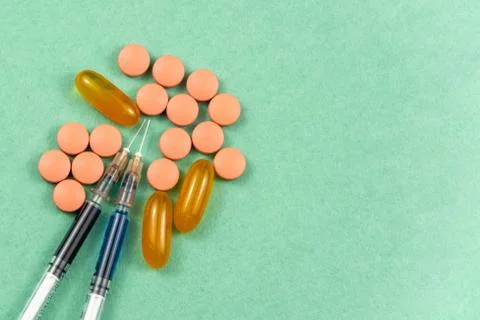 A syringe with an injection solution and vitamins with pills Stock Photos