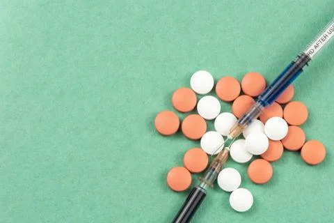 A syringe with an injection solution and vitamins with pills Foto stock
