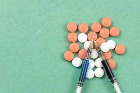 A syringe with an injection solution and vitamins with pills Stock Photos