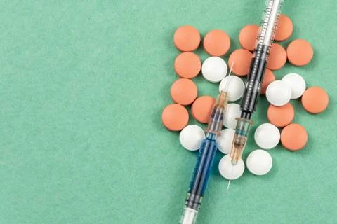 A syringe with an injection solution and vitamins with pills Stock Photos