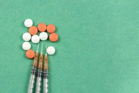 A syringe with an injection solution and vitamins with pills Stock Photos