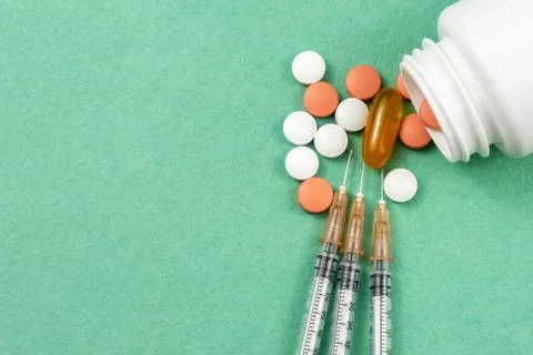 A syringe with an injection solution and vitamins with pills Stock Photos