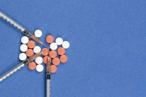 A syringe with an injection solution and vitamins with pills Stock Photos