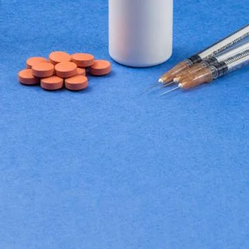 A syringe with an injection solution and vitamins with pills Stock Photos