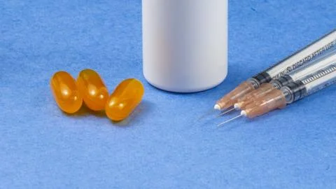 A syringe with an injection solution and vitamins with pills Stock Photos