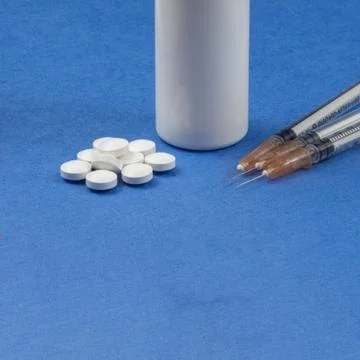 A syringe with an injection solution and vitamins with pills Stock Photos