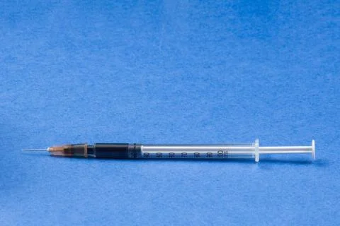 A syringe with an injection solution on a blue background Stock Photos