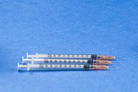 A syringe with an injection solution on a blue background Stock Photos