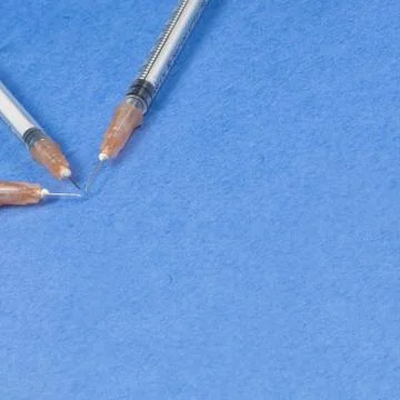 A syringe with an injection solution on a blue background Stock Photos