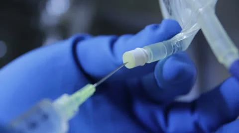 Syringe inserted and pushing fluids into an IV bag. Video stock 12737388