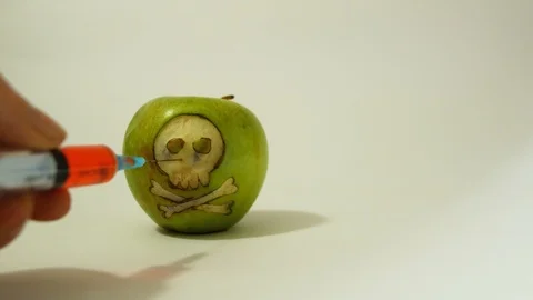 Syringe inserted into a green apple with an engraved skull, representative image Stock Footage 98293507