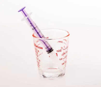 Syringe in measuringe cup Stock Photos