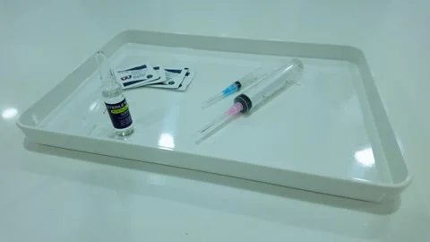 Syringe, needle, ampule vile and alcohol swab on a medical tray ready for Stock Footage 263528571