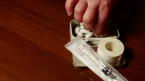 Syringe, plaster and tablets in an iron box. Female hands check the health 库存影片 86332381