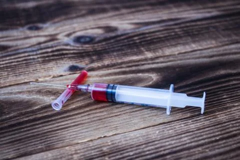 Syringe with red liquid on wooden background Stock Photos