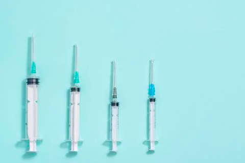Syringes of different sizes on a blue background close-up Stock Photos
