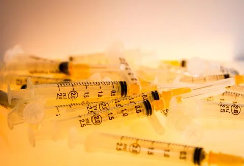 Syringes on orange background Stock Photos