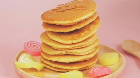 Syrup being poured onto stack of steaming pancakes on pink background. Stock-Footage 336589265