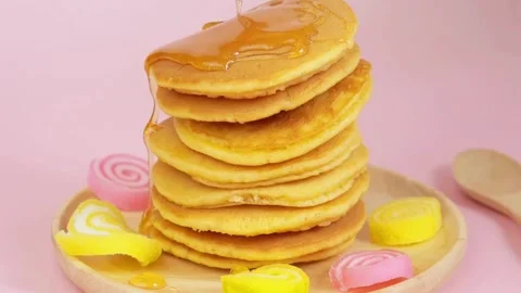 Syrup being poured onto stack of steaming pancakes on pink background. Stock-Footage 336589272