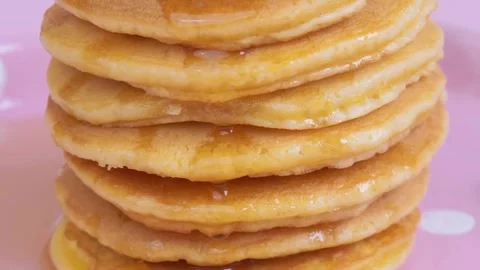 Syrup being poured onto stack of steaming pancakes on pink background. Stock-Footage 336589276