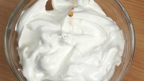 Syrup drops are added to white whipped cream. Slow motion Stock Footage 76135161