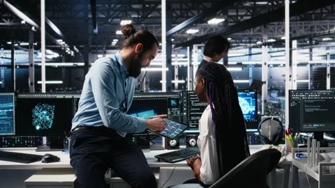System administrator and employee in data center coding with generative AI Stock Footage 313570928