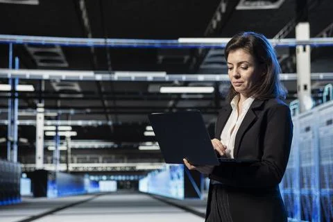 System administrator in data center using laptop, verifying firewall Stock Photos