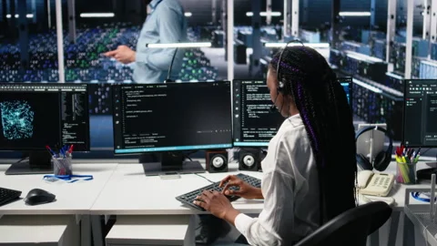 System administrator in data center wearing headset assisting users with AI Stock Footage 313566945